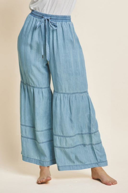 Washed denim tiered wide leg pants with drawstring waist and side pockets.